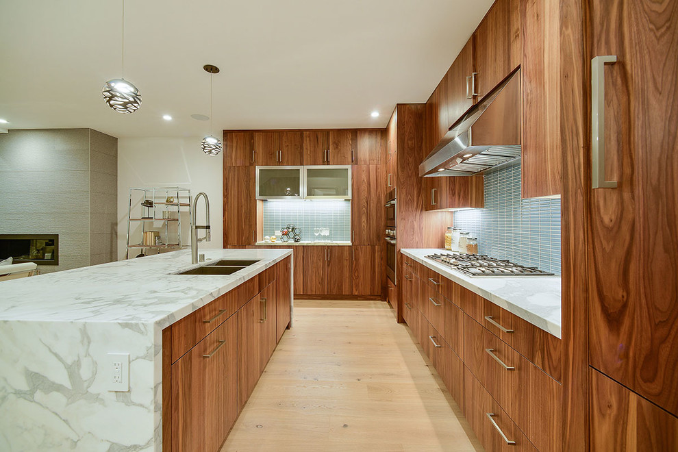 Photo of a large contemporary l-shaped open plan kitchen in San Francisco with flat-panel cabinets, dark wood cabinets, quartz benchtops, blue splashback, ceramic splashback, stainless steel appliances, light hardwood floors, with island, a double-bowl sink and brown floor.