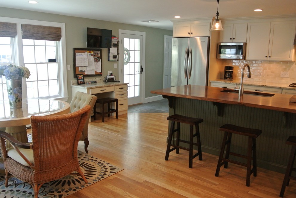 Eat-in kitchen - transitional galley light wood floor eat-in kitchen idea in Boston with an undermount sink, shaker cabinets, white cabinets, wood countertops, white backsplash, ceramic backsplash, stainless steel appliances, an island and brown countertops