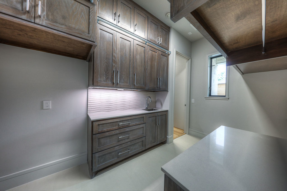 Large contemporary galley dedicated laundry room in Houston with an undermount sink, recessed-panel cabinets, distressed cabinets, quartz benchtops, grey walls, ceramic floors, a side-by-side washer and dryer, white floor and grey benchtop.