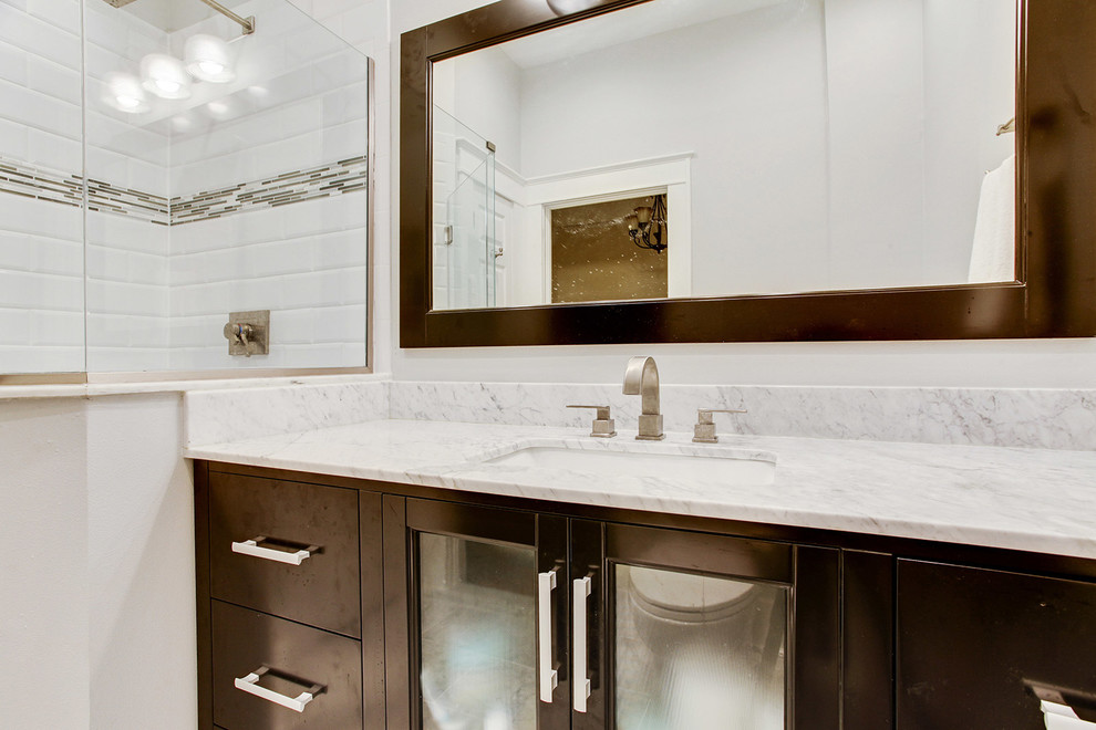 Large transitional master bathroom in New Orleans with an undermount sink, flat-panel cabinets, dark wood cabinets, marble benchtops, a corner shower, a two-piece toilet, white tile, stone tile, grey walls and marble floors.