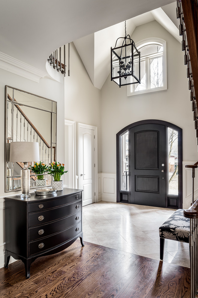 This is an example of a mid-sized traditional foyer in Toronto with beige walls, marble floors, a single front door, a black front door and beige floor.