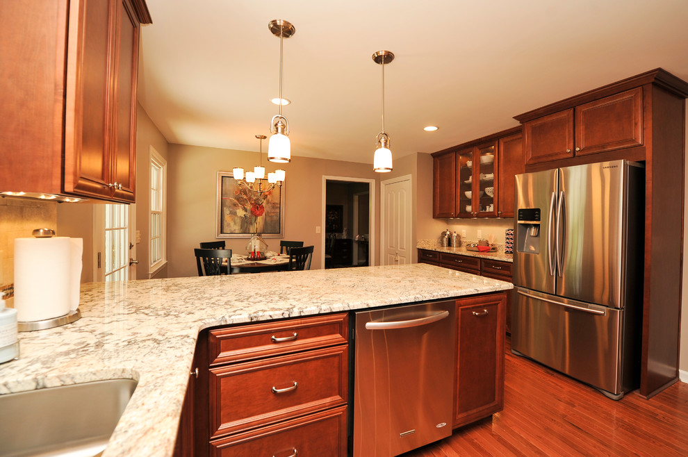 Inspiration for a mid-sized transitional u-shaped medium tone wood floor eat-in kitchen remodel in Birmingham with a double-bowl sink, flat-panel cabinets, medium tone wood cabinets, granite countertops, beige backsplash, stone tile backsplash, stainless steel appliances and a peninsula