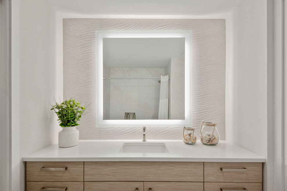 Maritim inredning av ett mellanstort vit vitt en-suite badrum, med släta luckor, skåp i ljust trä, ett badkar i en alkov, vit kakel, marmorkakel, bänkskiva i kvarts och beiget golv