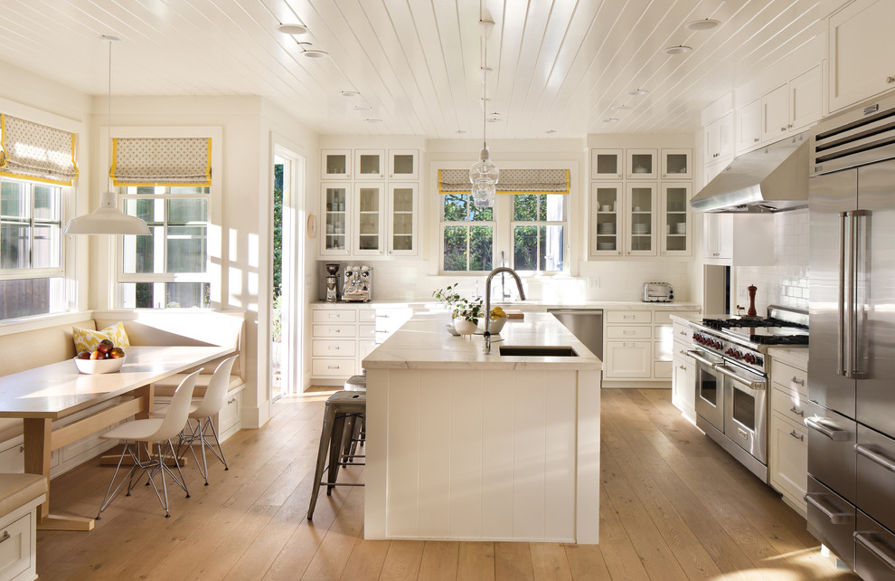 Inspiration for a traditional l-shaped eat-in kitchen in San Francisco with an undermount sink, shaker cabinets, white cabinets, white splashback, subway tile splashback, stainless steel appliances, medium hardwood floors and with island.