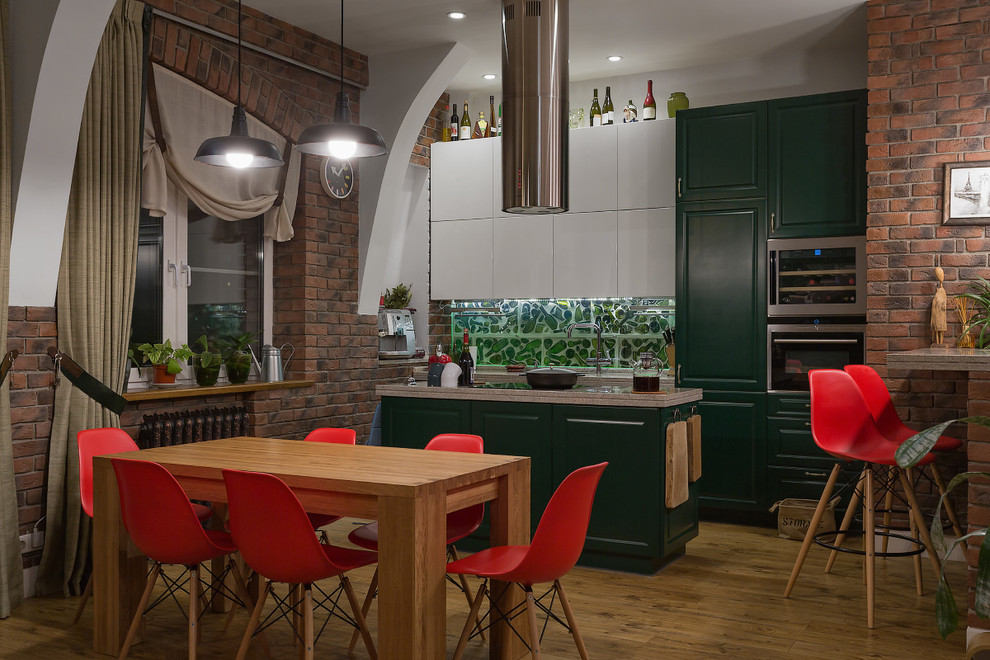 This is an example of an industrial eat-in kitchen in Moscow with raised-panel cabinets, green cabinets, green splashback, stainless steel appliances, medium hardwood floors and with island.