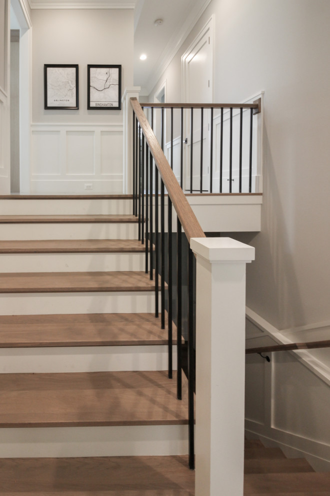 Large classic wood u-shaped wood railing staircase in DC Metro with wood risers and wainscoting.