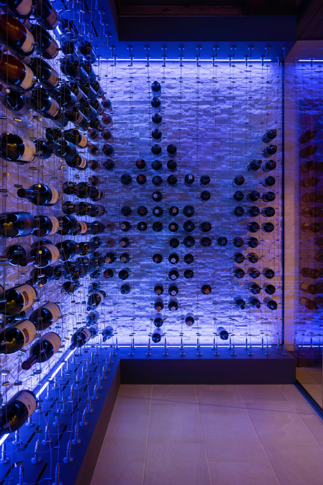 This is an example of an expansive wine cellar in Denver with ceramic floors, display racks and white floor.