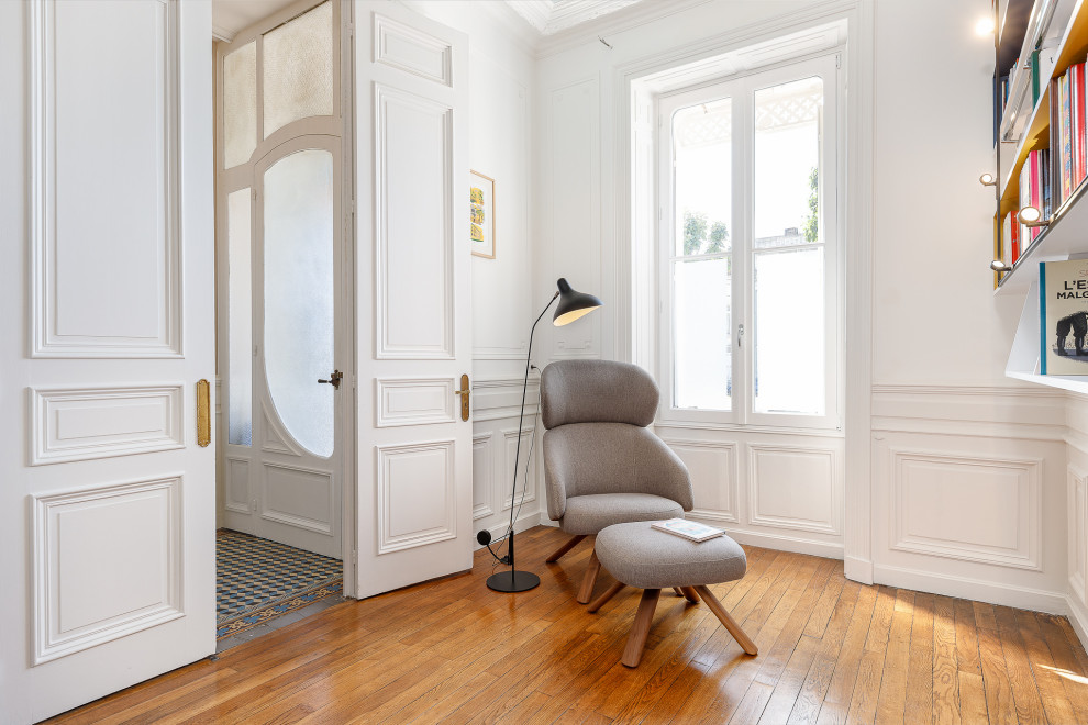 This is an example of a medium sized contemporary home office in Bordeaux with a reading nook, white walls, medium hardwood flooring, a freestanding desk, brown floors, a wallpapered ceiling and wainscoting.