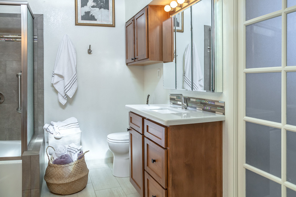 Inspiration for a large transitional master brown tile and porcelain tile porcelain tile and beige floor corner bathtub remodel in Phoenix with recessed-panel cabinets, medium tone wood cabinets, a one-piece toilet, beige walls, an undermount sink and quartz countertops