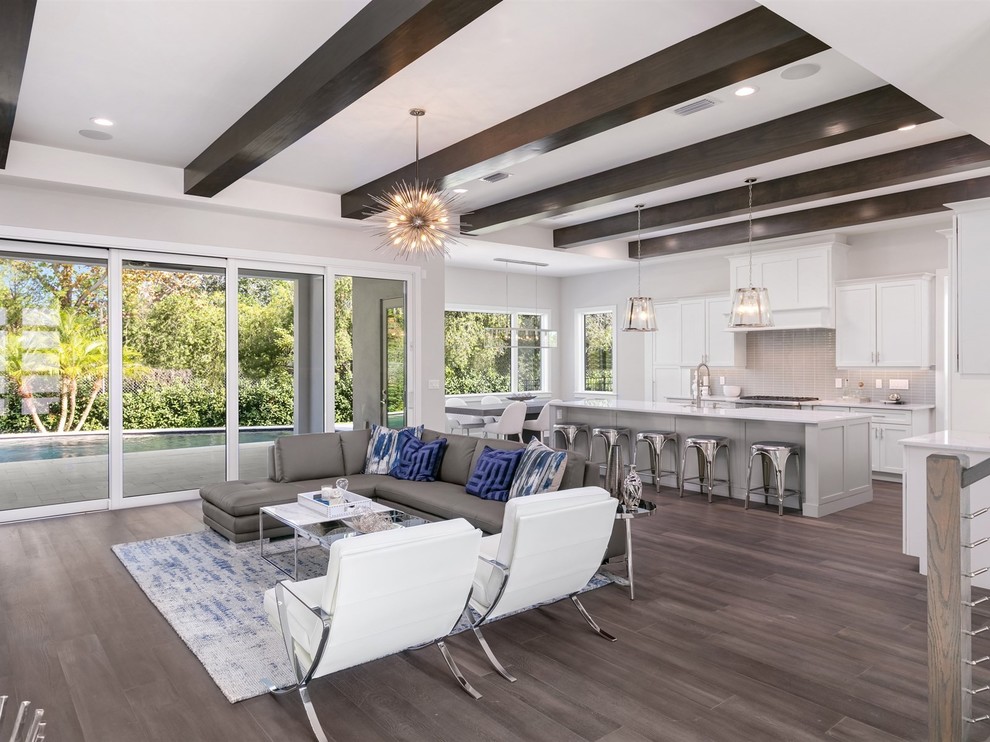 Design ideas for a mid-sized transitional open concept family room in Orlando with grey walls, dark hardwood floors, a wall-mounted tv and brown floor.