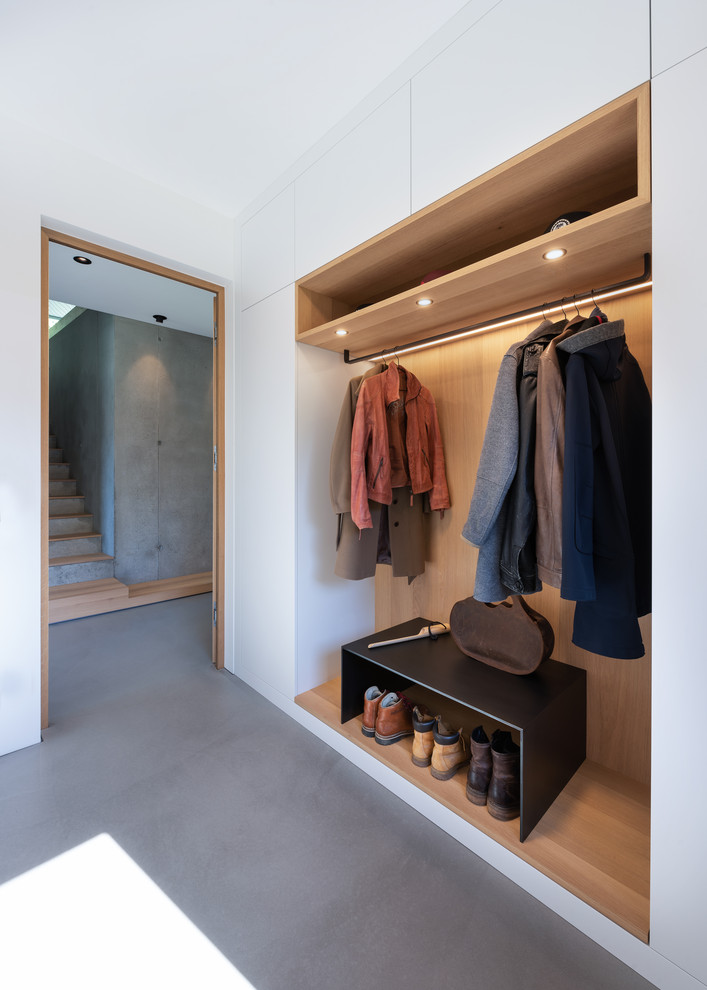 Photo of a scandinavian entryway in Munich with concrete floors, grey floor, white walls and wood walls.