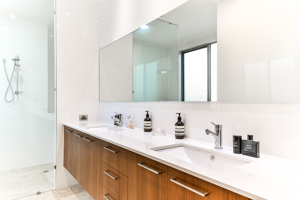 This is an example of a large contemporary master bathroom in Perth with flat-panel cabinets, medium wood cabinets, a double shower, a wall-mount toilet, beige tile, ceramic tile, white walls, ceramic floors, an undermount sink and engineered quartz benchtops.