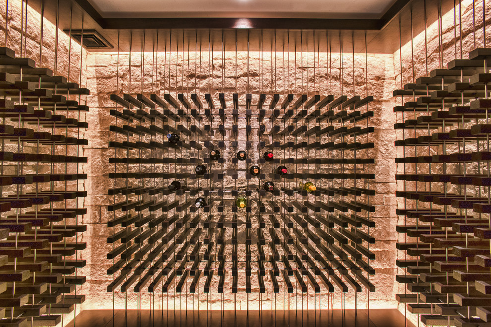 Photo of a contemporary wine cellar with travertine floors, display racks and grey floor.