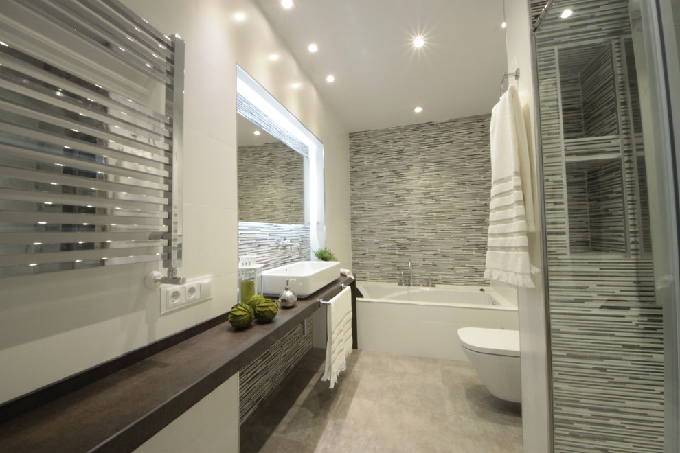 Photo of a mid-sized contemporary master bathroom in Madrid with a drop-in tub, an alcove shower, a one-piece toilet, gray tile, ceramic tile, white walls, ceramic floors, a vessel sink and engineered quartz benchtops.