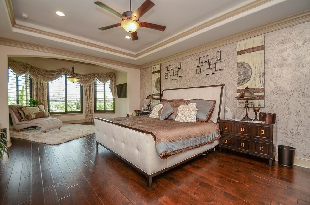 This is an example of a large mediterranean master bedroom in Houston with beige walls, dark hardwood floors, no fireplace and brown floor.