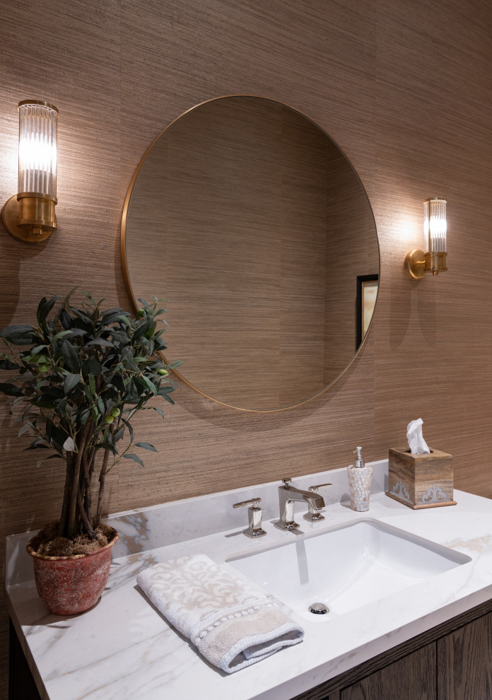 Inspiration for a mid-sized traditional powder room in Dallas with flat-panel cabinets, medium wood cabinets, a one-piece toilet, light hardwood floors, an undermount sink, marble benchtops, white benchtops, a freestanding vanity and wallpaper.