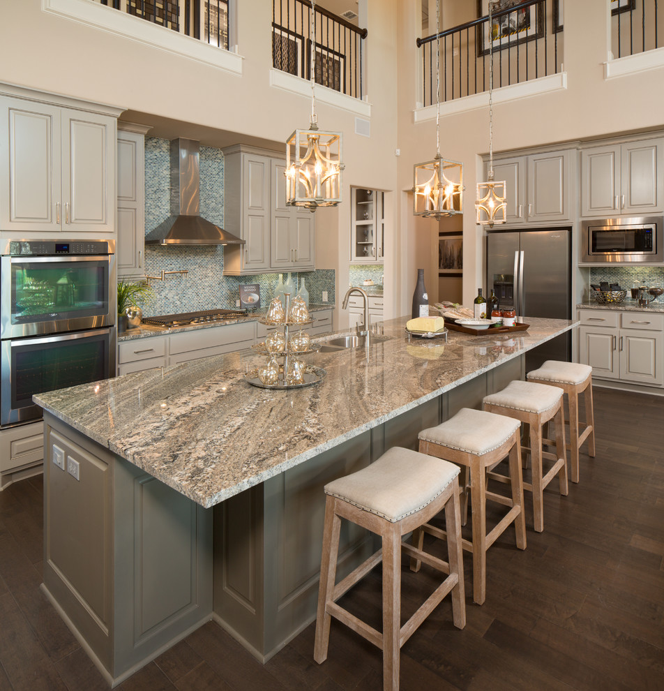 Inspiration for a transitional l-shaped dark wood floor kitchen remodel in Austin with an undermount sink, raised-panel cabinets, gray cabinets, blue backsplash, mosaic tile backsplash, stainless steel appliances, an island and gray countertops