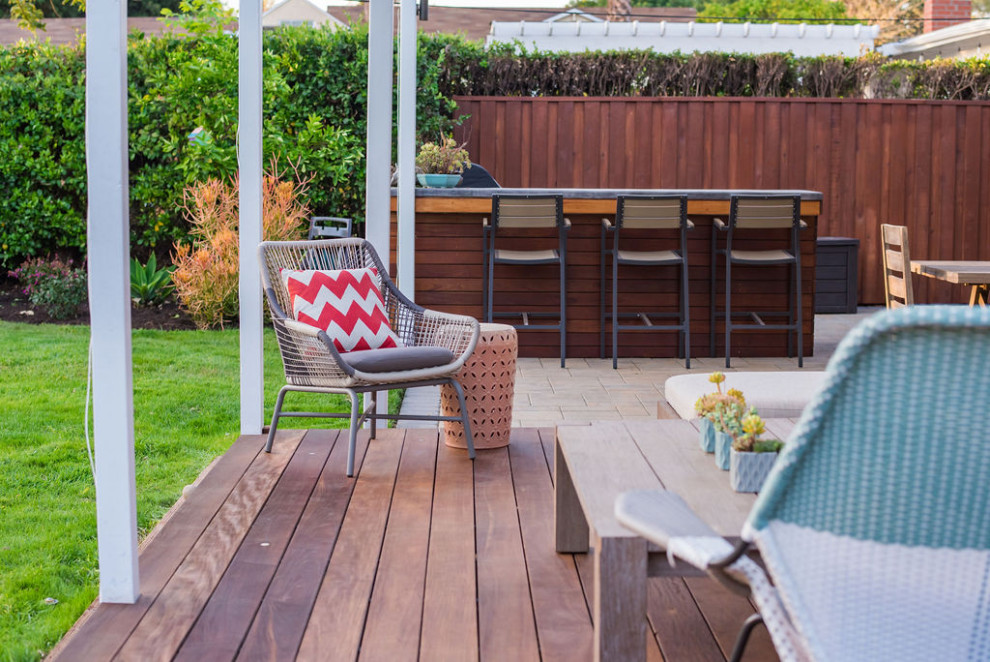 This is an example of a mid-sized contemporary full sun backyard wood fence landscaping in Los Angeles with a pergola and decking for spring.