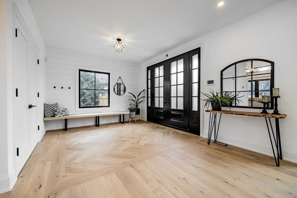 Großes Landhaus Foyer mit weißer Wandfarbe, hellem Holzboden, Doppeltür, schwarzer Haustür und Holzdielenwänden in Toronto