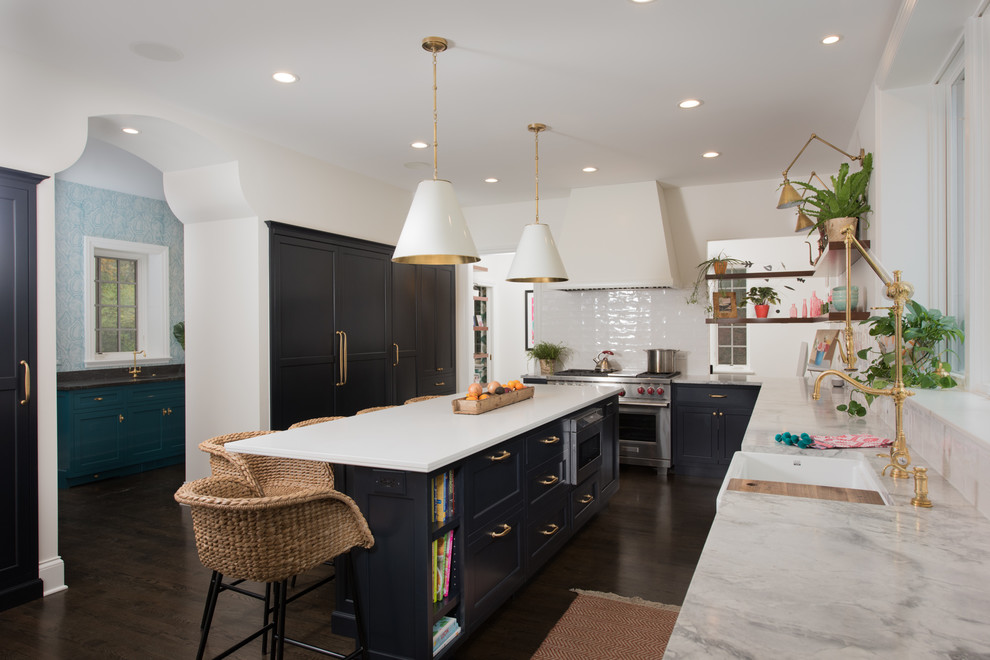 This is an example of a transitional l-shaped kitchen in Chicago with a farmhouse sink, white splashback, stainless steel appliances, dark hardwood floors, with island and brown floor.