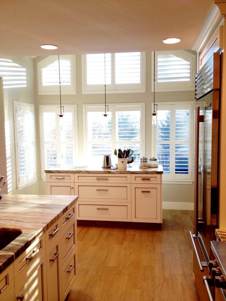 Inspiration for a mid-sized transitional l-shaped light wood floor open concept kitchen remodel with a double-bowl sink, shaker cabinets, white cabinets, white backsplash, subway tile backsplash, stainless steel appliances, an island and marble countertops