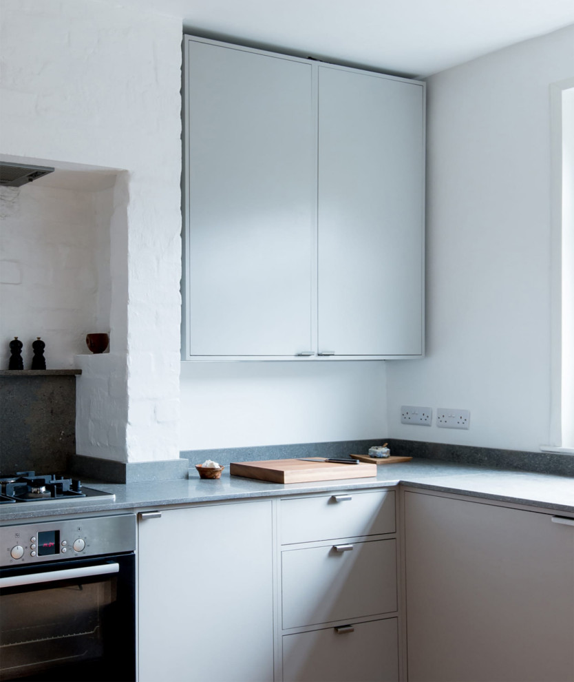 Modern inredning av ett litet grå grått kök, med en dubbel diskho, släta luckor, grå skåp, bänkskiva i kalksten, grått stänkskydd, stänkskydd i kalk, rostfria vitvaror och korkgolv