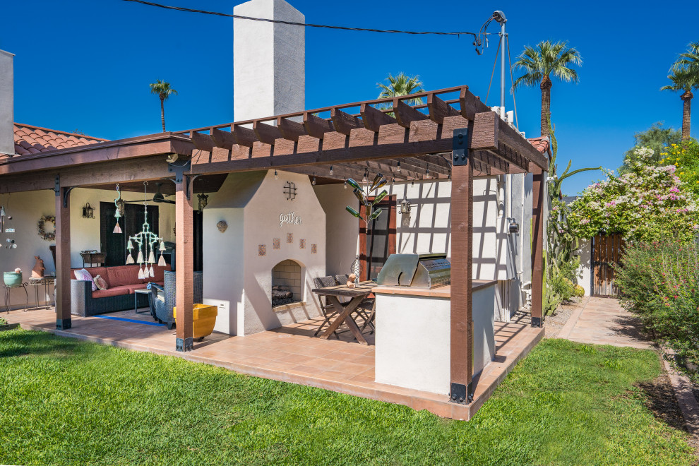 Example of a southwest backyard tile patio design in Phoenix with a fireplace and a pergola