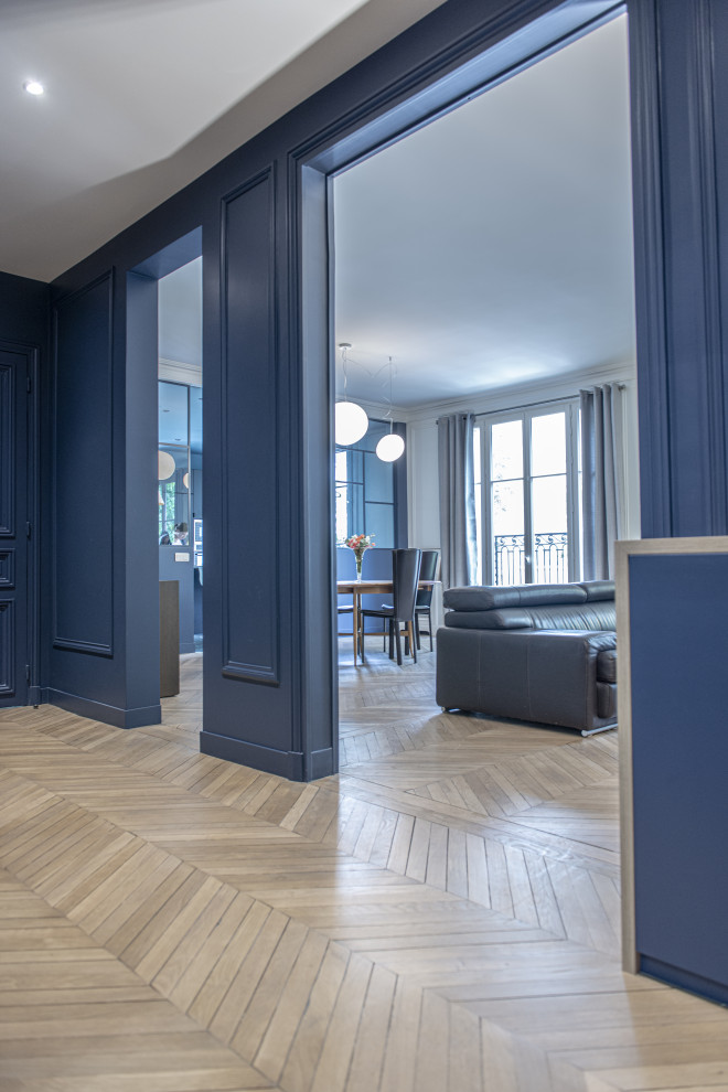 Источник вдохновения для домашнего уюта: большая открытая гостиная комната в современном стиле с синими стенами, светлым паркетным полом, бежевым полом и панелями на части стены