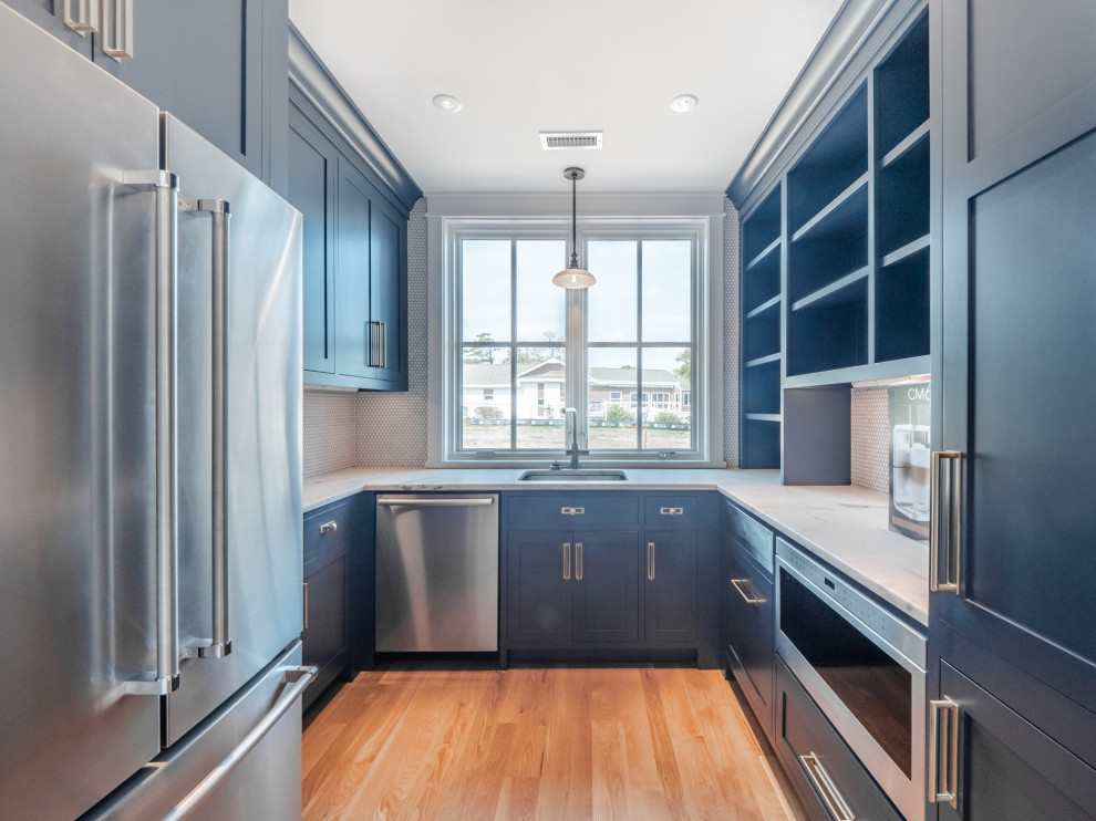 Bild på ett lantligt flerfärgad flerfärgat kök, med en rustik diskho, blå skåp, marmorbänkskiva, vitt stänkskydd, stänkskydd i mosaik, rostfria vitvaror, ljust trägolv och en köksö