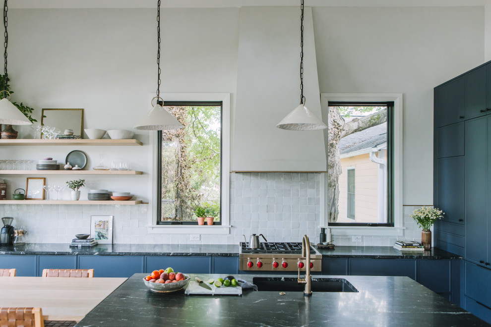Inredning av ett skandinaviskt mellanstort svart svart kök, med en enkel diskho, skåp i shakerstil, blå skåp, granitbänkskiva, vitt stänkskydd, stänkskydd i keramik, rostfria vitvaror, ljust trägolv, en köksö och gult golv