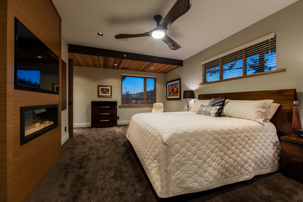 Inspiration for a large arts and crafts master bedroom in Vancouver with carpet, brown walls, brown floor, a ribbon fireplace and a wood fireplace surround.