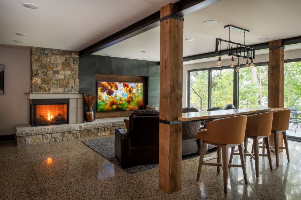 Large country walk-out basement in Minneapolis with a home bar, grey walls, concrete floors, a corner fireplace, a stone fireplace surround and multi-coloured floor.