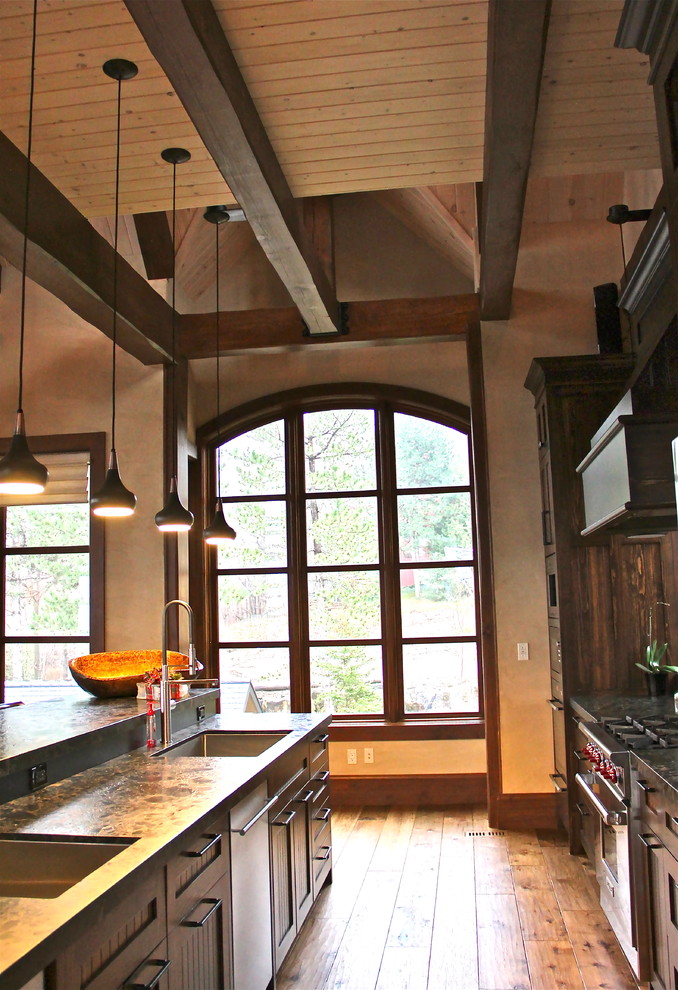 Photo of a country galley eat-in kitchen in Toronto with an undermount sink, louvered cabinets, dark wood cabinets, granite benchtops, stainless steel appliances, medium hardwood floors and no island.