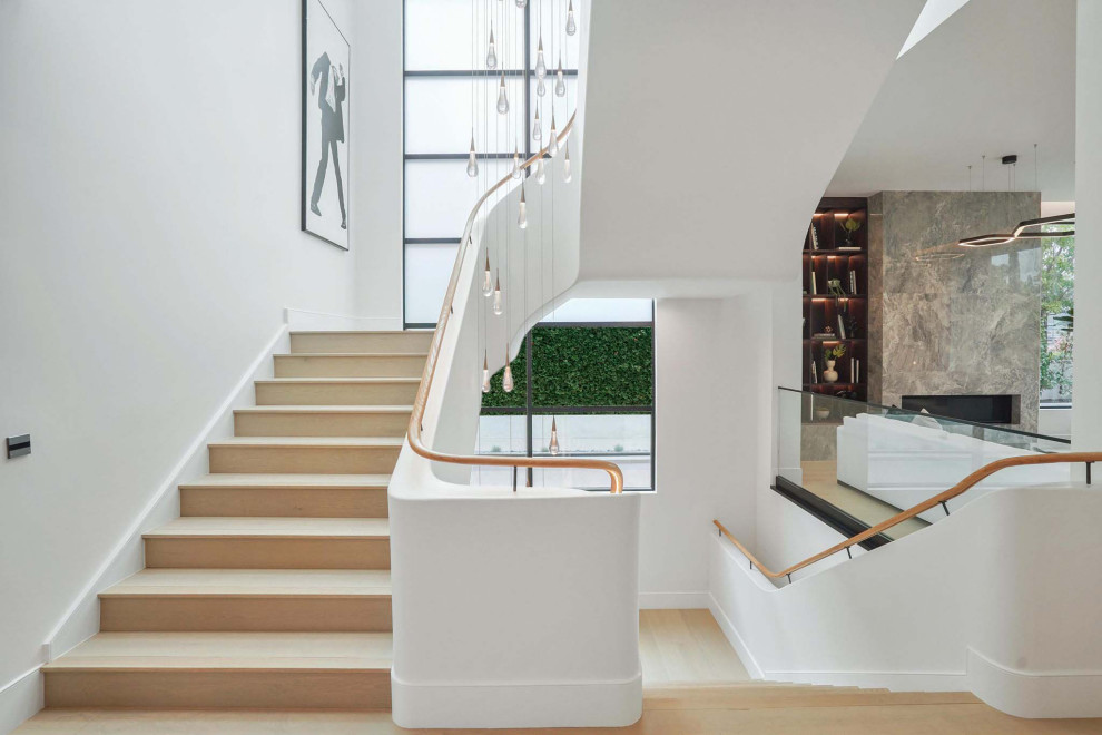 Cette photo montre un grand escalier courbe moderne avec des marches en bois, des contremarches en bois et un garde-corps en bois.