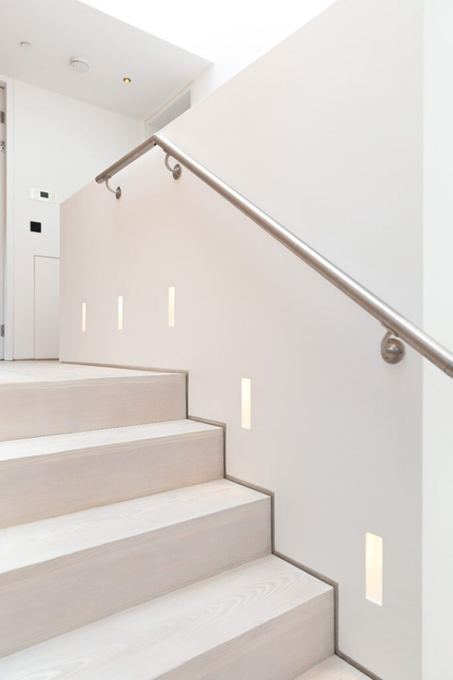Photo of a mid-sized scandinavian concrete straight staircase in London with concrete risers, metal railing and decorative wall panelling.