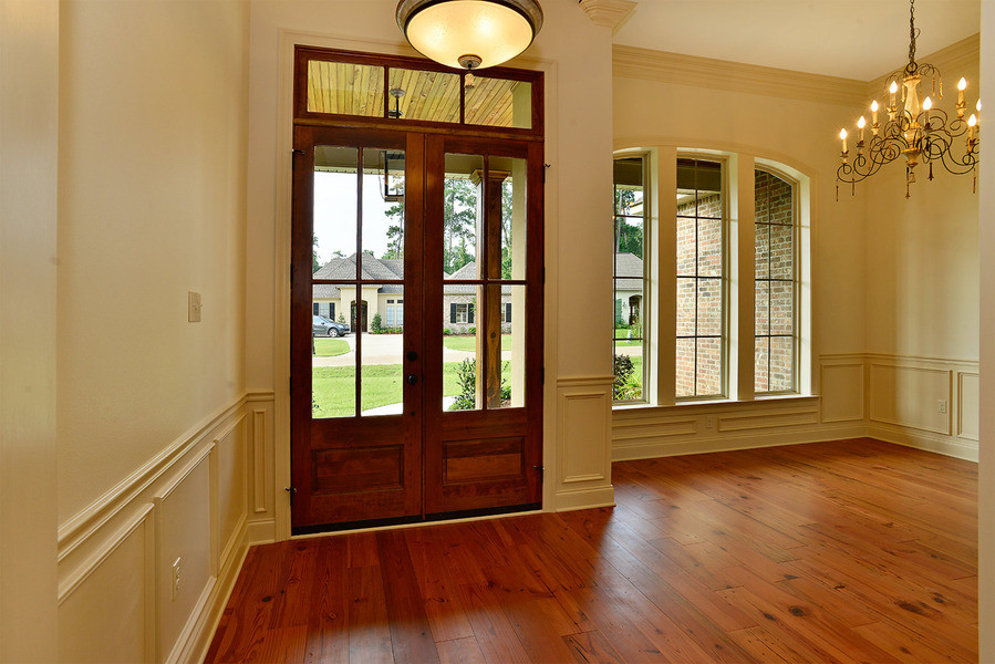 This is an example of a country entryway in New Orleans with dark hardwood floors, a double front door and a dark wood front door.