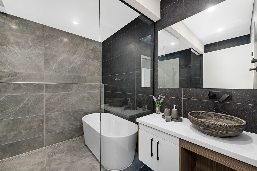 Inspiration for a contemporary master bathroom in Melbourne with flat-panel cabinets, white cabinets, a freestanding tub, an open shower, gray tile, grey walls, a vessel sink, marble benchtops, grey floor, an open shower and white benchtops.