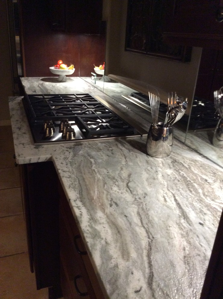 Example of a mid-sized transitional terra-cotta tile kitchen design with a double-bowl sink, granite countertops, stainless steel appliances and a peninsula