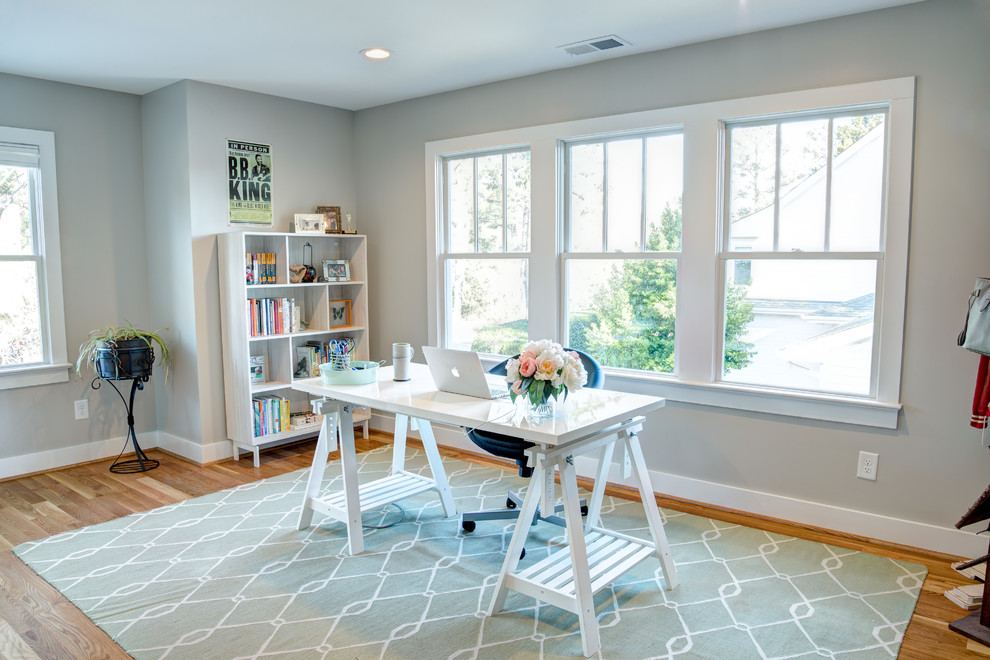 Transitional home office in Raleigh with grey walls, light hardwood floors and a freestanding desk.