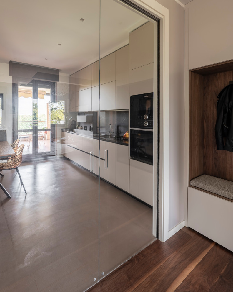 Photo of a large modern galley enclosed kitchen in Milan with dark hardwood flooring, brown floors, a drop ceiling, a double-bowl sink, flat-panel cabinets, beige cabinets, composite countertops, brown splashback, porcelain splashback, black appliances, no island and brown worktops.