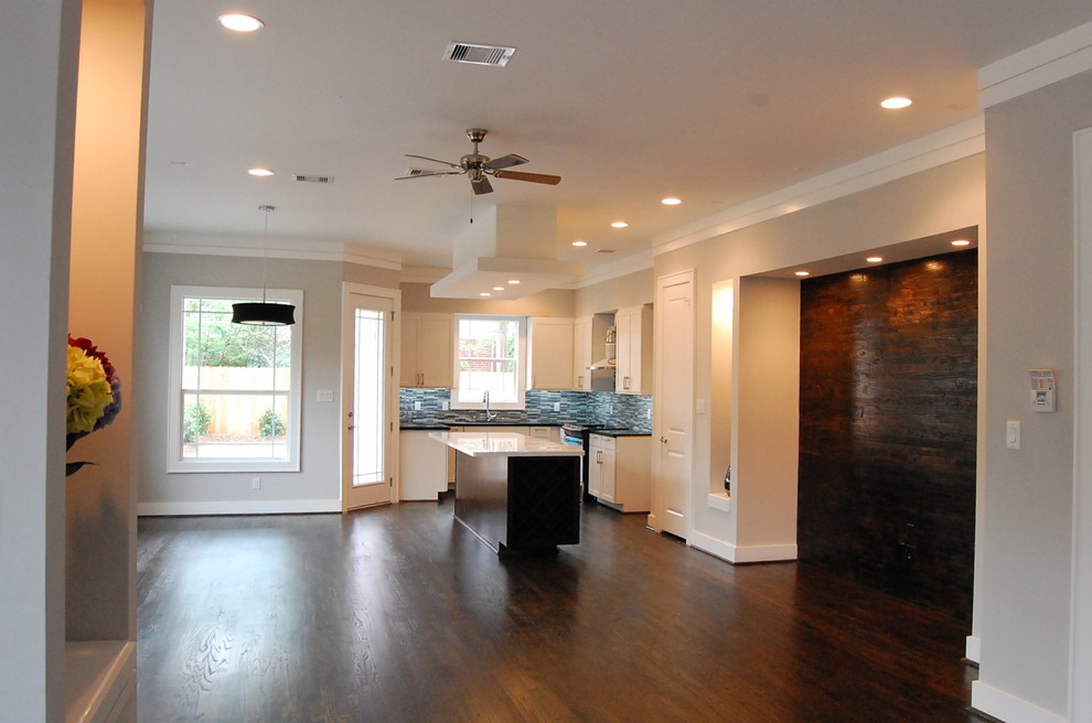 This is an example of a mid-sized contemporary formal open concept living room in Houston with grey walls, dark hardwood floors and a wall-mounted tv.