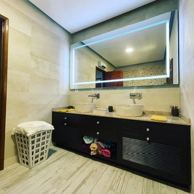 Modern inredning av ett mellanstort beige beige en-suite badrum, med luckor med lamellpanel, bruna skåp, ett platsbyggt badkar, en dusch i en alkov, en vägghängd toalettstol, beige kakel, porslinskakel, beige väggar, ljust trägolv, ett nedsänkt handfat, marmorbänkskiva och vitt golv