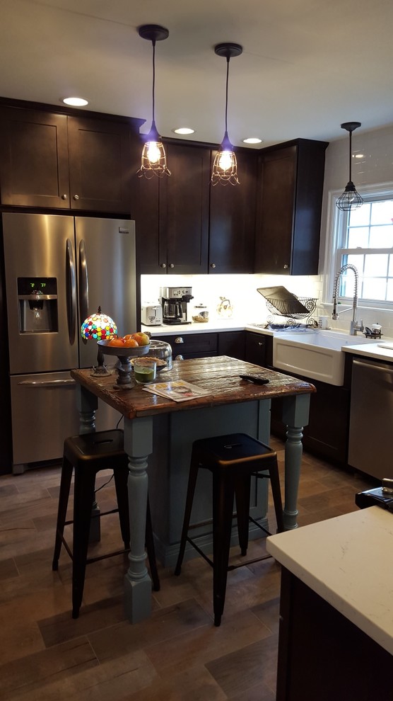 Mid-sized mountain style u-shaped porcelain tile eat-in kitchen photo in Indianapolis with a farmhouse sink, shaker cabinets, dark wood cabinets, wood countertops, white backsplash, ceramic backsplash, stainless steel appliances and an island