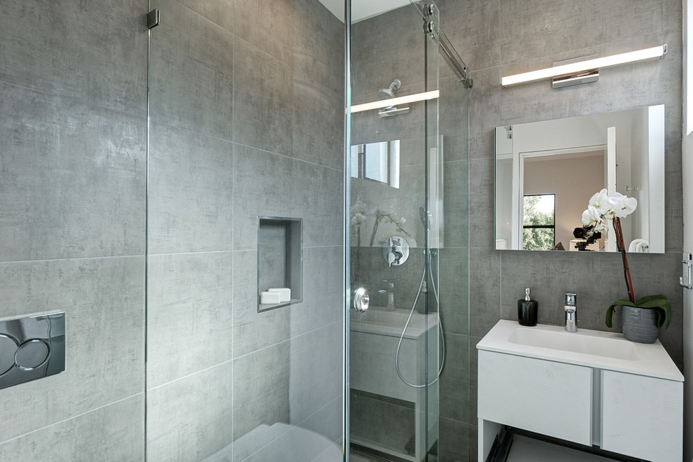 Design ideas for a mid-sized contemporary 3/4 bathroom in San Francisco with flat-panel cabinets, white cabinets, an alcove shower, a wall-mount toilet, gray tile, porcelain tile, white walls, porcelain floors, an integrated sink, engineered quartz benchtops, beige floor and a hinged shower door.