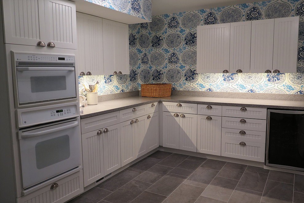 Inspiration for a mid-sized transitional l-shaped slate floor eat-in kitchen remodel with shaker cabinets, stainless steel cabinets, laminate countertops, multicolored backsplash, wood backsplash, white appliances and no island