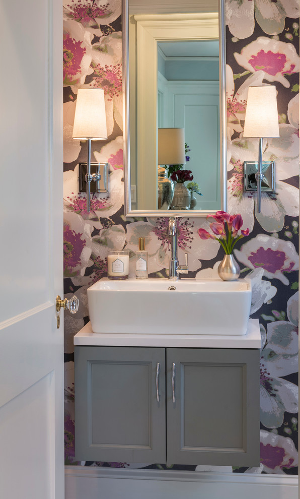 Photo of a small beach style powder room in Providence with shaker cabinets, grey cabinets, multi-coloured walls, a vessel sink and white benchtops.