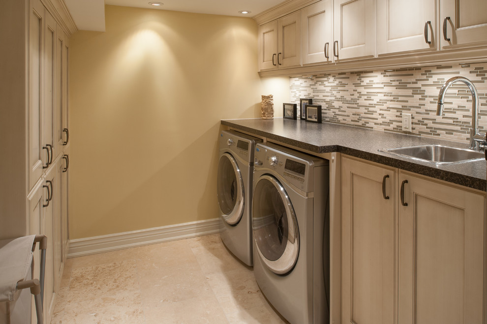 Photo of a large traditional galley utility room in Toronto with a drop-in sink, beaded inset cabinets, beige cabinets, laminate benchtops, limestone floors, a side-by-side washer and dryer and beige walls.