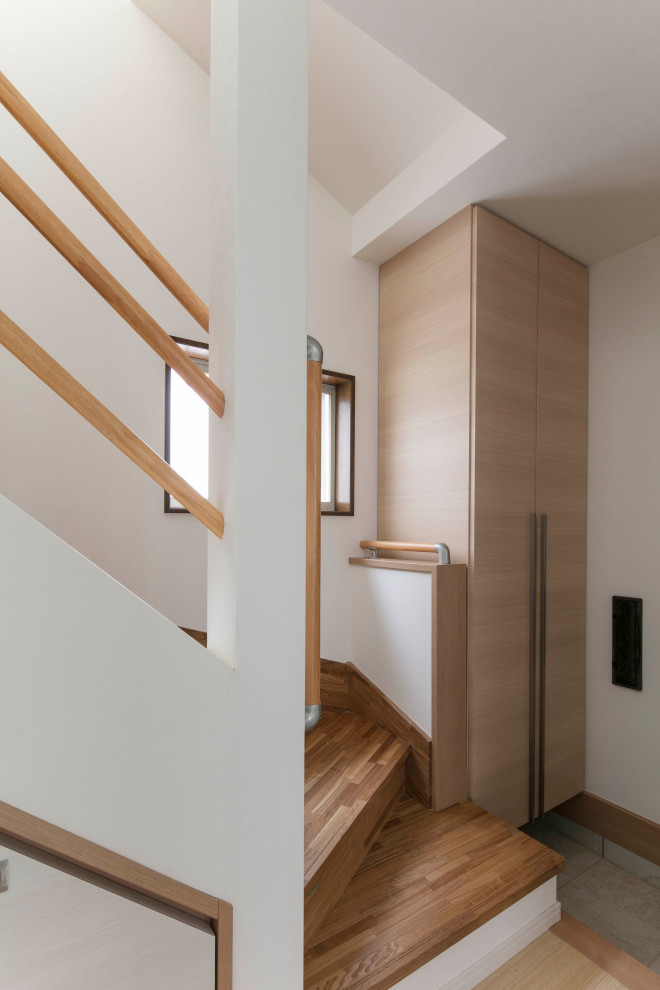 Bild på en liten minimalistisk l-trappa i trä, med sättsteg i trä och räcke i trä
