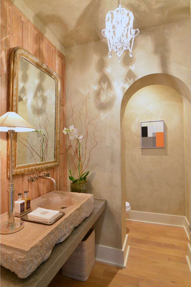 Mid-sized powder room in Other with a two-piece toilet, beige walls, light hardwood floors, an integrated sink, limestone benchtops and beige benchtops.