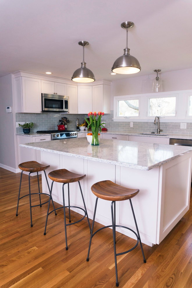 Inspiration for a mid-sized traditional l-shaped eat-in kitchen in Boston with a double-bowl sink, flat-panel cabinets, white cabinets, quartzite benchtops, blue splashback, subway tile splashback, stainless steel appliances, dark hardwood floors, with island, brown floor and grey benchtop.